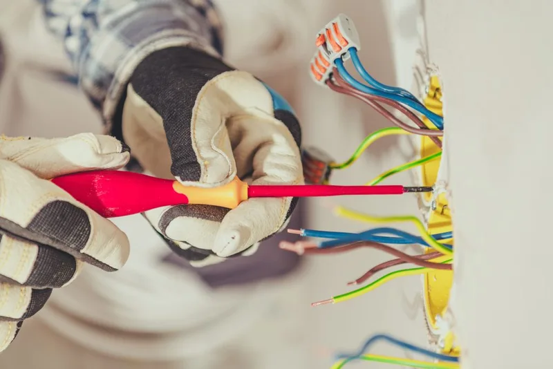 Electrician preparing a wall outlet for installation